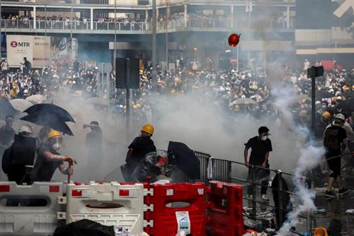 Người biểu tình phản ứng với hơi cay trong cuộc biểu tình hôm 12.6 - Ảnh: Reuters