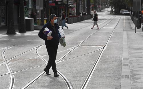 Một người dân Melbourne tranh thủ đi mua nhu yếu phẩm trước giờ giới nghiêm ban đêm bắt đầu từ ngày 16-8 - Ảnh: AFP
